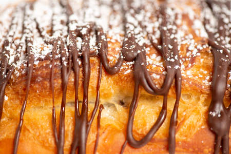 Freshly baked croissant filled with chocolate and sprinkled with icing sugar