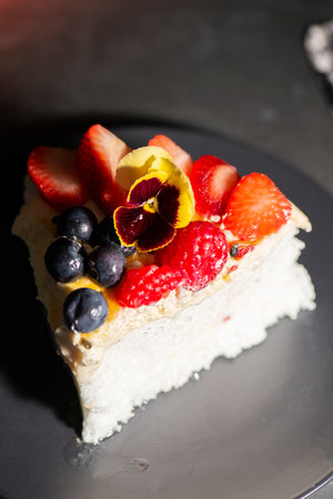Slice of pavlova, an Australian dessert, with fresh fruit including strawberries, raspberries,...