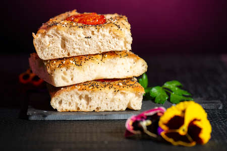 Fresh baked focaccia with cherry tomato, poppy and sesame seeds, pepper, Himalayan rock salt and mixed herbs.の写真素材