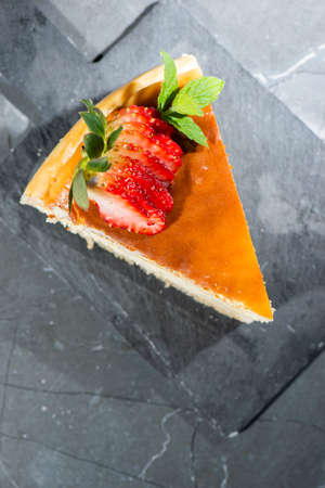 Homemade Traditional Cheesecake with fresh mint and sliced strawberries.の写真素材