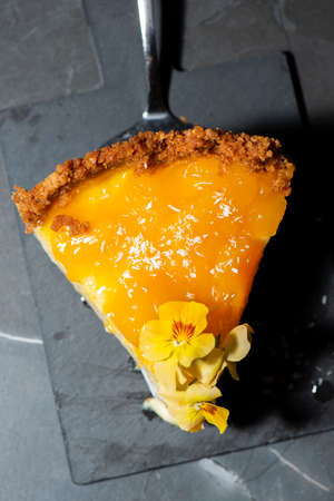 Homemade mango and coconut cheesecake with fresh edible flowers.