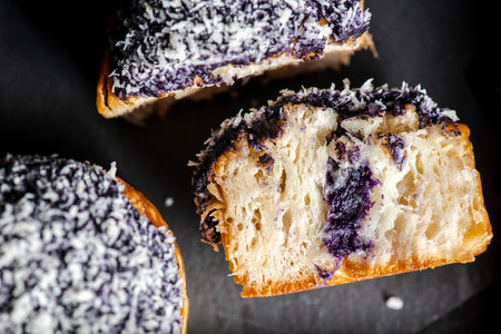 A cruffin is a hybrid of a croissant and a muffin. The pastry is made by proofing and baking laminated dough in a muffin mould. The cruffin is then filled with various creams, jams or curds, and then garnished. This cruffin has Ube filling.の写真素材