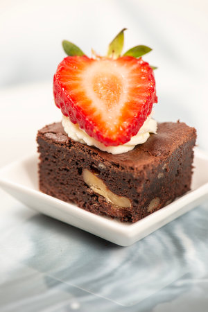 Deliciously rich cake brownie slice with Chantilly cream and fresh strawberry.の写真素材