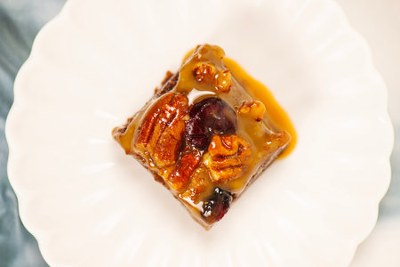 Piece of caramel cake with raisins and nuts on white plateの写真素材