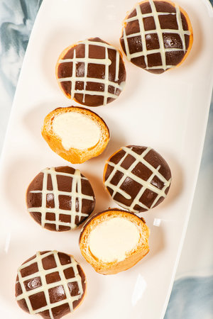 Six pack of gluten free profiteroles covered in milk and white chocolate and filled with fresh...