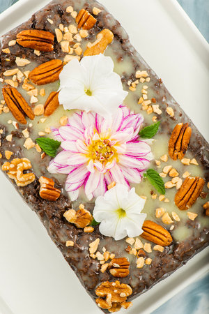 Freshly baked chocolate loaf cake with a variety of crushed nuts.の写真素材