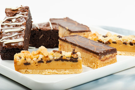Selection of gourmet gluten free sweets including macadamia crumble, caramel and brownie slices.の写真素材