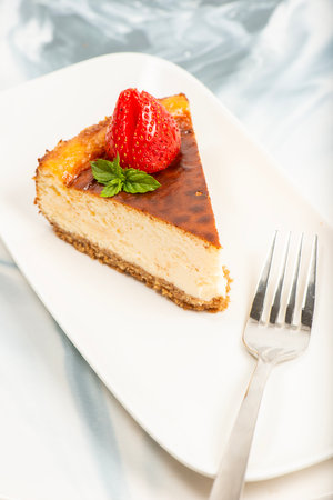 Creamy New York Cheesecake topped with fresh flowers, mint leaves, and strawberries.の写真素材