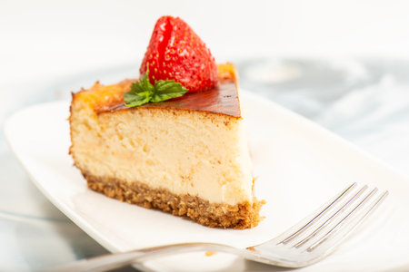 Creamy New York Cheesecake topped with fresh flowers, mint leaves, and strawberries.の写真素材