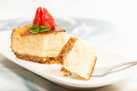 Creamy New York Cheesecake topped with fresh flowers, mint leaves, and strawberries.の写真素材