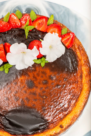Creamy New York Cheesecake topped with fresh flowers, mint leaves, and strawberries.の写真素材