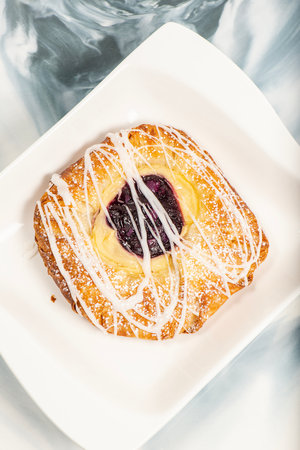 Mouth-watering blueberry and custard danish topped with white fondant and icing sugar.の写真素材