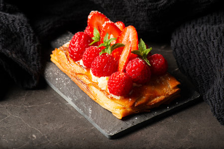 Delicious mixed berry Danish with custard, raspberries, and strawberries dusted with icing sugar and decorated with mint leaves.の写真素材