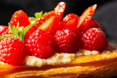 Delicious mixed berry Danish with custard, raspberries, and strawberries dusted with icing sugar and decorated with mint leaves.の写真素材