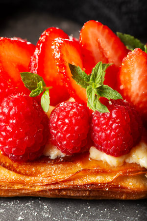 Delicious mixed berry Danish with custard, raspberries, and strawberries dusted with icing sugar and decorated with mint leaves.の写真素材