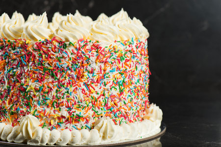 Delicious birthday-themed butter cake with buttercream icing and rainbow sprinklesの写真素材