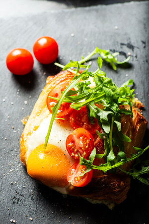 Homemade savoury breakfast Danish with a free-range egg, cherry tomatoes and fresh rocket.の写真素材