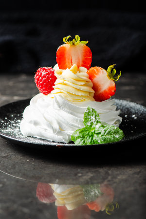 Crispy baked Italian meringue with a marshmallow center, filled with Chantilly cream, topped with fresh strawberries and raspberries.の写真素材