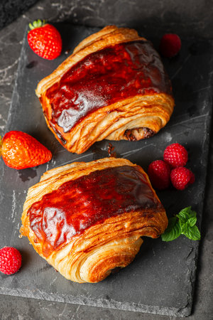 Delectable golden brown baked Pain au chocolat with fresh summer fruit.の写真素材