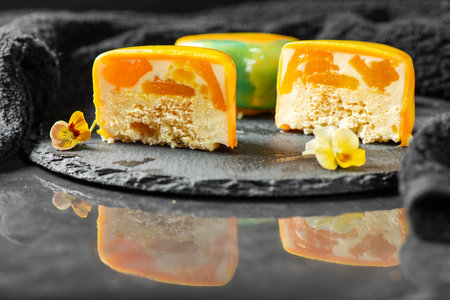 Gourmet Entremet with layered sponge cake, mango jelly and mousse, covered in a mirror tropical coloured mirror glaze.の写真素材