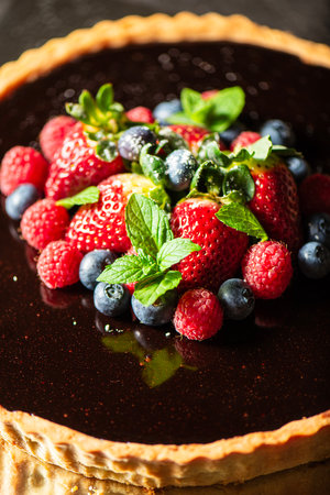 Delectable home made Chocolate Tart with rich shortcrust pastry, flourless chocolate cake, creamy ganache and dark chocolate icing, topped with fresh berries.の写真素材