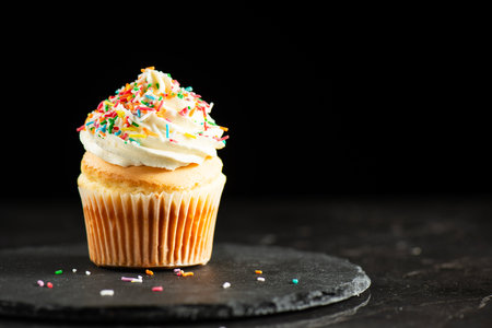 Soft and delicate vanilla cupcake with buttercream and rainbow sprinkles.の写真素材
