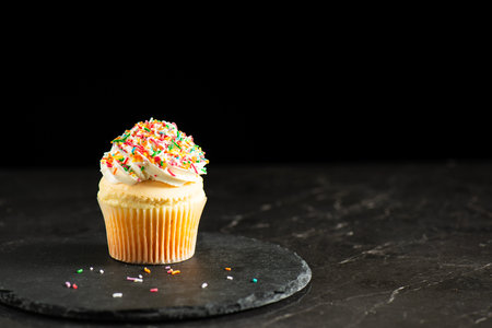Soft and delicate vanilla cupcake with buttercream and rainbow sprinkles.の写真素材