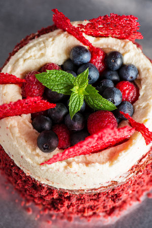 Red Velvet Cake with Mascarpone Cream Cheese, decorated with fresh raspberries, blueberries, and coral tuile.の写真素材
