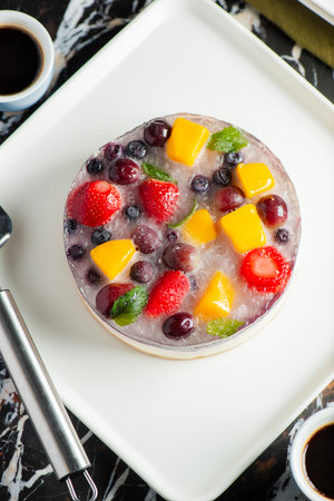 Delicious and light no-bake cheesecake with summer fruits including strawberry, mango, and grapes.の写真素材