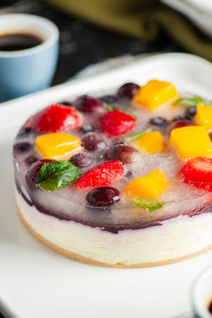Delicious and light no-bake cheesecake with summer fruits including strawberry, mango, and grapes.の写真素材