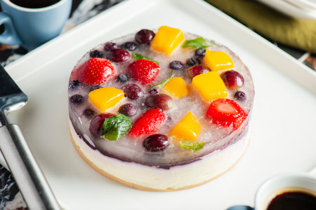 Delicious and light no-bake cheesecake with summer fruits including strawberry, mango, and grapes.の写真素材