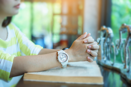 Woman praying on holy bible in the morning. Teenager hand with Bible praying. Hands folded in prayer on a Holy Bible in church concept for faith, spirituality and religion. Victory concept for god.の写真素材