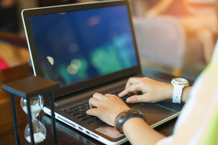 Business women are typing reports hastily with an hourglass placed side by side. Deadline conceptの写真素材