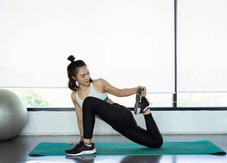 Young woman doing yoga exercises on yoga mat at fitness gym. health concept.