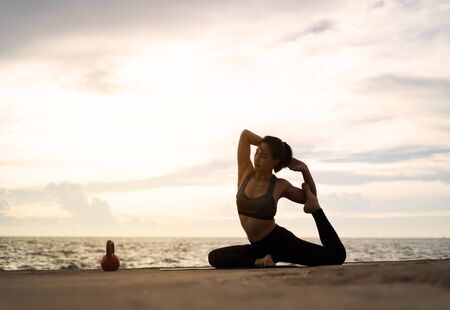 woman practicing yoga during surrealistic sunset at the seaside. healthy concept and workout.