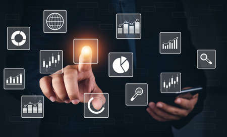 Man touching stock market virtual icons. Business man using Big data for analytics and business intelligence (BI) with chart and graph icons on a digitals screen interface. Online digital and market.の写真素材