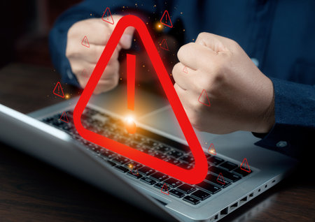 A hacker attacks and hacks data on computers. A businessman is using a computer with a triangle caution warning sign for notification error and maintenance concept. cybercrime, security, ransomware.の写真素材
