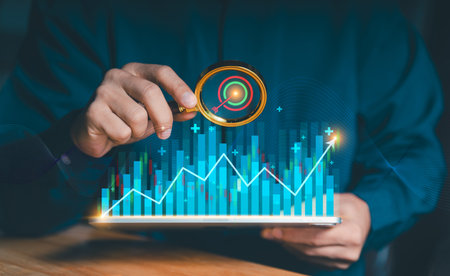Target business success concept. Hand holding magnifying glass over financial growth graph and...
