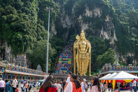 Kuala Lumpur, Malaysia - August 30, 2024: The massive golden statue of Lord Murugan at the base of Batu Caves, with the colorful rainbow steps leading up to the limestone caves in Kuala Lumpur.の写真素材