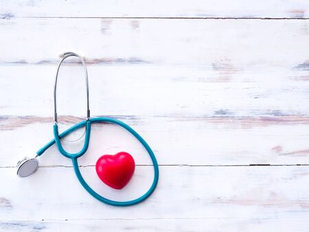 The Stethoscope is surrounded by the red heart, a concept of health care. On the wooden floor with cracksの写真素材