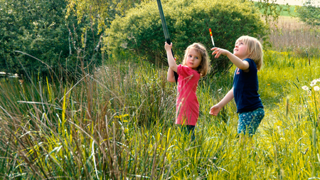Two little girls are ejecting together the fishing rodの写真素材
