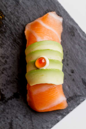 Raw Salmon Sushi Topping with Avocado and Ikura (Salmon Roe) Served on Black Stone Plate.の写真素材