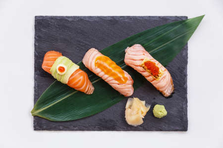 Torched and Raw Salmon Sushi Set Topping with Avocado, Mayonnaise and Ikura, Sauce and Cheese with Ebiko Served with Wasabi and Prickled Ginger on Black Stone Plate.の写真素材