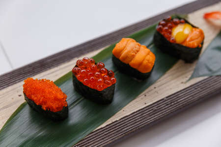 Sushi Set Include Tobiko, Ikura, Sea Urchin and Ikura, Urchin and Quail Egg Yolk Served on Leaf on Stone Plate.の写真素材
