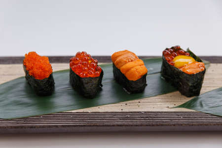 Sushi Set Include Tobiko, Ikura, Sea Urchin and Ikura, Urchin and Quail Egg Yolk Served on Leaf on Stone Plate.の写真素材