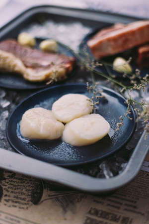 Beef, Pork, and Scallop Preparing for Cooking on Iced Plate with Olive Oil, Wine, Half of Onion and Black Pepper on Newspaper.の写真素材