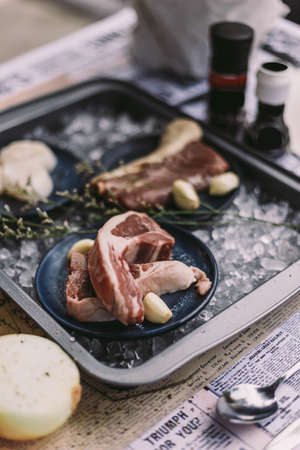 Beef, Pork, and Scallop Preparing for Cooking on Iced Plate with Olive Oil, Wine, Half of Onion and Black Pepper on Newspaper.の写真素材