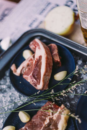 Beef, Pork, and Scallop Preparing for Cooking on Iced Plate with Olive Oil, Wine, Half of Onion and Black Pepper on Newspaper.の写真素材