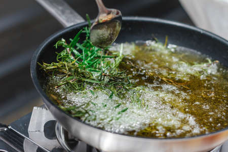 Chef Fried Rosemary Leaves in Olive Oil in a Pan for Making Rosemary Oil.の写真素材