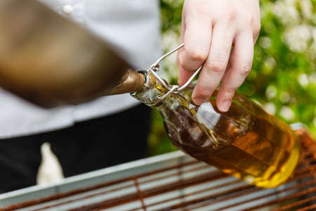 Chef Pouring Rosemary Oil From Pan in The Glass Bottle with Paper Cone.の写真素材